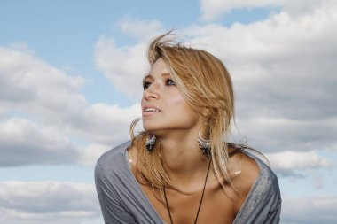 Güzel bir sarışın portresi. Şık bir yaz gri kısa sarı saçlı kızı bir bulutlu gökyüzü adam karşı