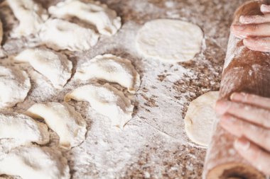 Vareniki hazırlanması. Kadının ellerini dışarı hamur rulo. Tablo yalan çiğ köfte yanında beyaz flou