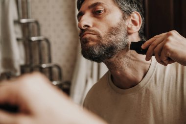 sakal düzeltici düzeltici. Adam bağımsız olarak gri sakalı bir makine ile keser