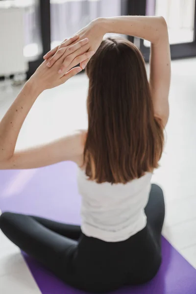 Cute graceful girl with long hair in tights engaged in yoga on a lilac ru