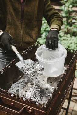 Mangal piknik sonra temizlik. Eller mangal dar bir kürek ile fırça. Külleri bir plastik containe kazıklı