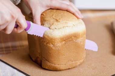 kadının elinde bir somun ekmek kapat-u dişleri olan büyük bir leylak bıçakla kesilir