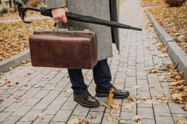 Beyefendi bekliyor. Şık ayakkabı ve beyaz bir ceket bir adam sonbahar park dar bir cadde üzerinde duruyor. Bir şemsiye ve ba