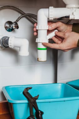 Su tesisatının elleri mutfak hidrolik deklanşör sistemini söküyor. Boru anahtarının yanında.