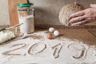 Yeni yıl mutfakta. 2019 un içinde bulunmakta. Hamur parçası holding eller. Yumurta ve granit counterto üzerinde duran bir cam kase