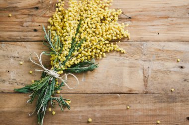 Bahar Etude. Sarı Mimoza dalı ahşap kurullarında yer almaktadır. Buket ile bir rop sargılı