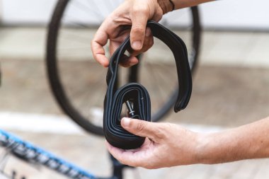 Motosikletin kamerasını değiştiriyorum. Bisikletçinin elleri metal uçlu kauçuk bir hazne tutuyor.