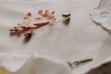 Sonbahar natürmort. Bir meşe ve bobin bir iplik ile büyük bir sarı yaprak beyaz keten üzerinde yatıyordu. Yakınlarda bir yüksük ve makas olduğunu