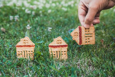 inanılmaz şirin bir evi. Bir ev şeklinde üç çerezleri üzerinde yeşil çayır yakın dur. Adamın elini koyar bir hous
