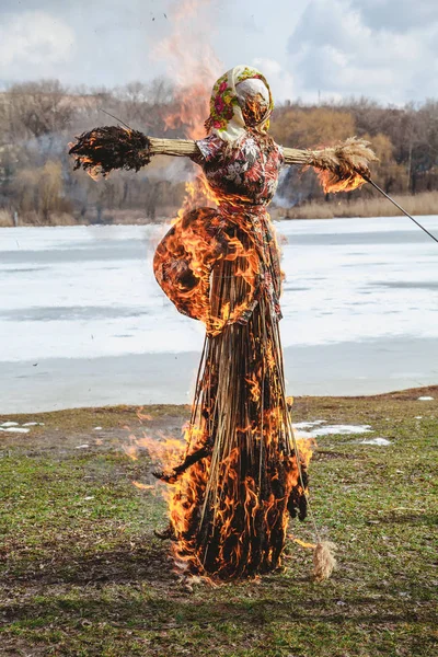 Slavic holiday of the end of winter. A large Shrovetide doll from straw burns on the river bank