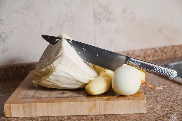 切蔬菜 一把带金属河的大刀子在白白菜的割头上伸出来 关闭板上是一个去皮保加利亚 — 图库照片
