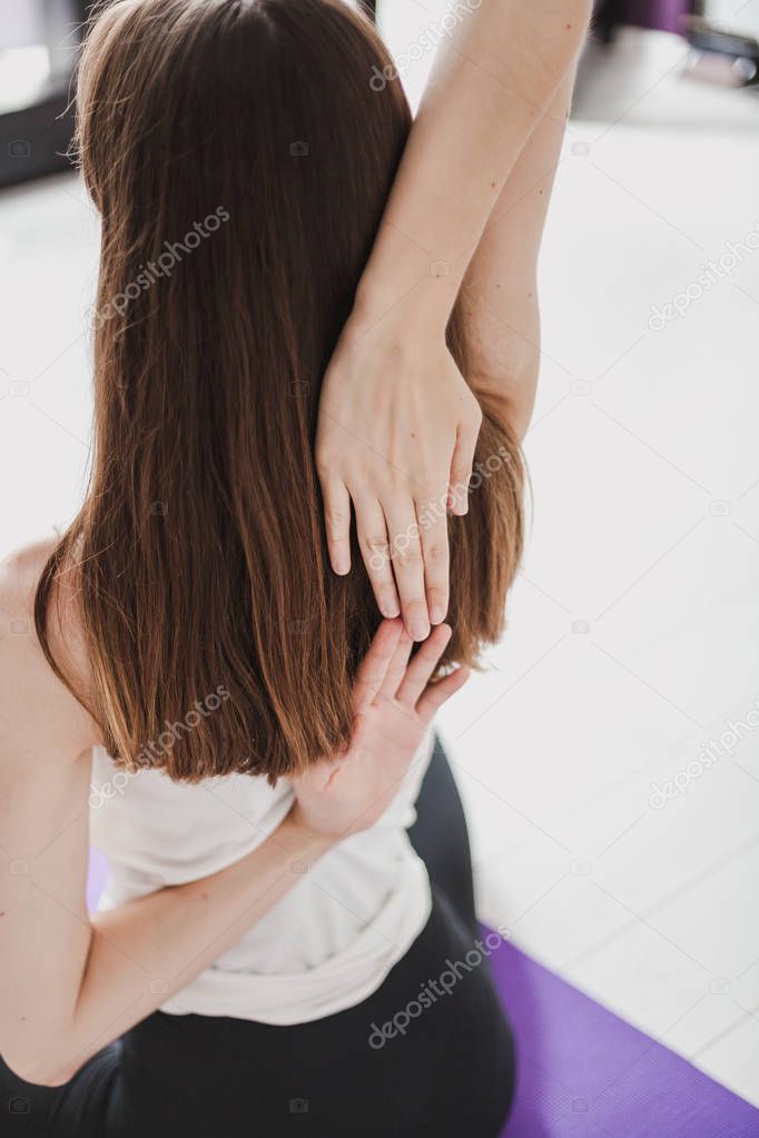 Cute graceful girl with long hair in tights engaged in yoga on a lilac ru