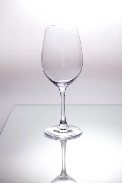 Empty transparent glass wine glass stands on a glass closeup. The reflection is visible below