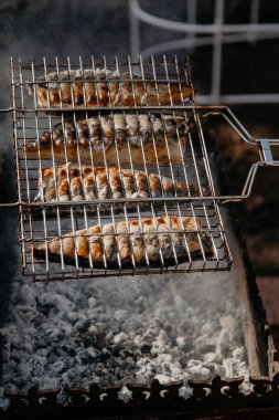 Izgara balık. Çelik ızgaralı dört uskumru ızgarada beyaz kömürlerin üzerinde hazır.