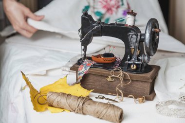 Bir dikiş makinesi ile sonbahar natürmort. Vintage dikiş makinesi ve konu skein. Sarı akçaağaç yaprağı yanında yatıyor. Branda ile embroider