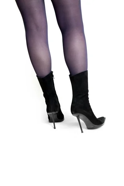 细长的女性腿在时尚的黑色绒面革靴子与一个白色的背景高薄的脚跟 后比赛 — 图库照片