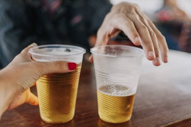 Cinsiyet farkı. Bir el manikür olan bir kadın ile bir bardak bira tutar. İkinci adam elinde kısmen fille camdır