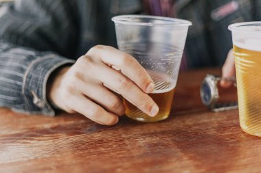 sağ kolum eksik bir plastik bardak bira ile tutar. Yakınlarda bir bardak arı olduğunu