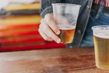 sağ kolum eksik bir plastik bardak bira ile tutar. Yakınlarda bir bardak arı olduğunu