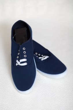 Beyaz tabanlı ve bağcıklı iki yeni mavi spor ayakkabı beyaz, izole bir arka planda duruyor.