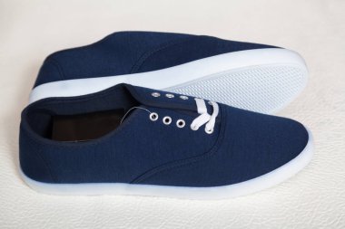 Beyaz tabanlı ve bağcıklı iki yeni mavi spor ayakkabı beyaz, izole bir arka planda duruyor.