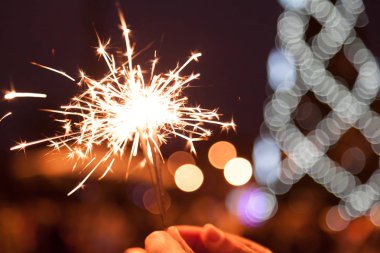 Kentsel Noel ağacı yanan zemin karşı erkek elinde maytap yakmak