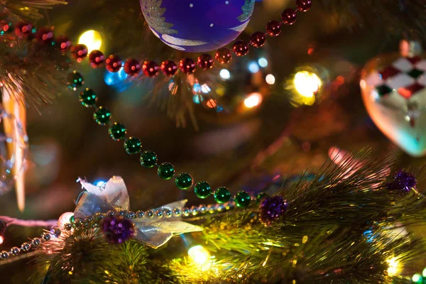 小さなボールに掛かっているトウヒのクリスマス ツリーの緑枝のクローズ アップから赤と緑のガーランド ぼやけてライト周辺のボール — ストック写真
