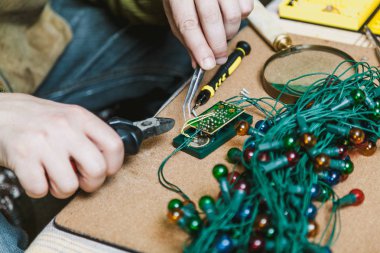 Yeni yıla hazırlanıyorduk. Köknar ağacı elektrik çelengi tamiri. Bir elektrikçinin, makasın ve cımbızın ellerinde