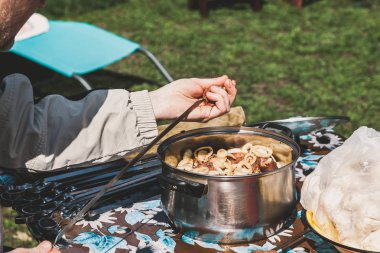 Şiş kebap hazırlanması. Eller iş parçacığı bir şiş üzerinde salamura et parçası. Bir tencereye et ve soğan adet geçerli