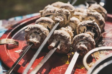 İştah açıcı ham mantar petrol beyaz soslu çelik şiş üzerinde yuvarlak bir tepsi üzerinde yalan