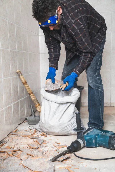 Builder Collects Pieces Floor Tiles White Bag Small Room Close — Stock Photo, Image