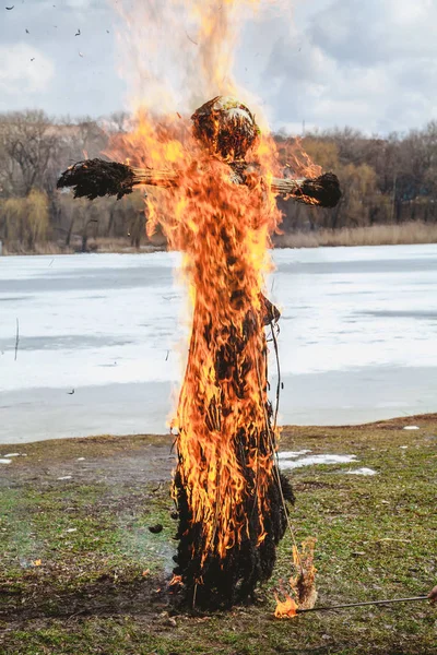 Slavic holiday of the end of winter. A large Shrovetide doll from straw burns on the river bank