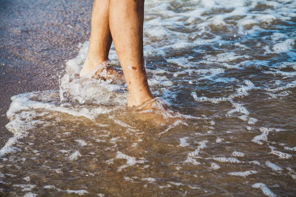 Yaz güneşli bir günde deniz sahilinde dalgalanan kadın ayakları 