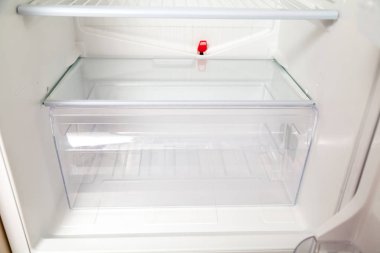 rectangular plastic box stands on the bottom shelf of an empty modern refrigerato clipart