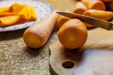 Kesme sebze. Büyük Olgun kırmızı havuç bir ahşap tahta üzerinde yatıyor. Keskin bir bıçak içinde yapıştırma