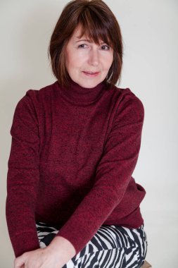 Parlak bir tek sesli arka plan üzerinde oturan Rötuş olmadan bir kadın portresi. Bordo kazaklı fram bakarak gülümseyen yaşlı güzel kadın