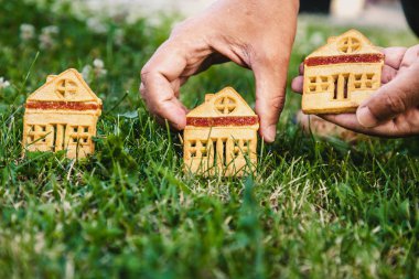 inanılmaz şirin bir evi. Bir ev şeklinde üç çerezleri üzerinde yeşil çayır yakın dur. Adamın elini koyar bir hous