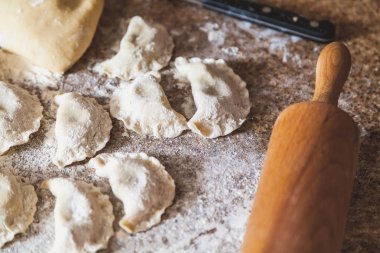 Mermer masa üstü beyaz un içinde çiğ köfte var. Yanındaki ahşap haddeleme pi