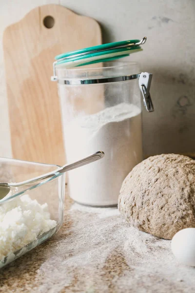 Cooking the pie. A piece of dough, flour, eggs and a glass jar are on a granite countertop