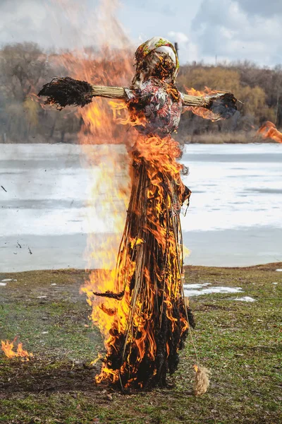 Slavic holiday of the end of winter. A large Shrovetide doll from straw burns on the river bank