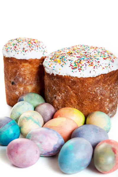 Two Easter cakes and several multi-colored originally painted chicken eggs on a white backgroun