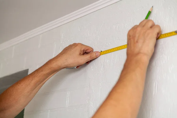 As mãos fazem a marcação de parede com fita métrica e lápis — Fotografia de Stock