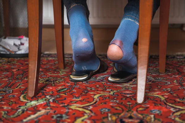 Человек сидит на стуле на носках и видит дырки. — стоковое фото