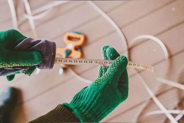 Hands in gloves wipe tape of  large tape measure