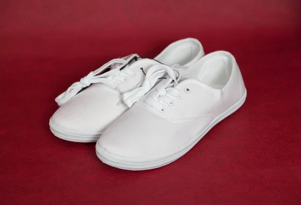 Coppia di sneakers bianche in piedi su sfondo rosso . — Foto Stock