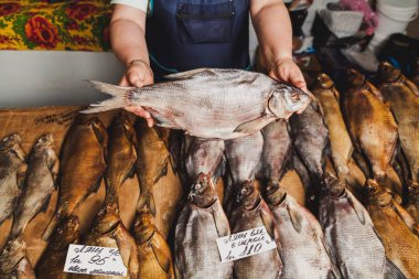 Bir kadının ellerini tezgahın üzerinde büyük bir çipura tutmak