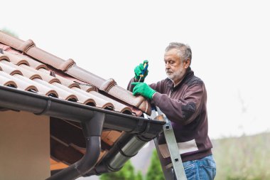 Man repairs a tiled roof of house close up clipart