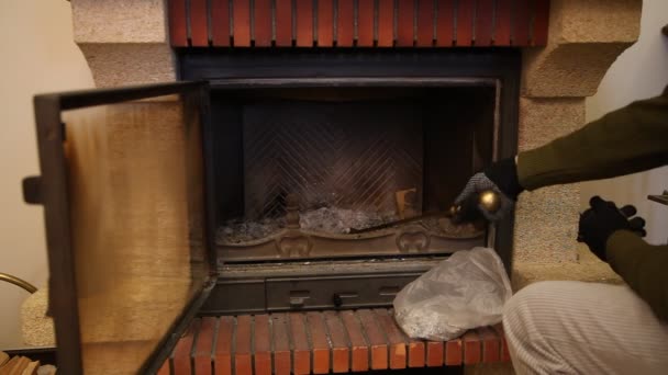 我们用黄铜铲把灰烬中清理壁炉 清洁壁炉 戴手套的手收集灰从壁炉与黄铜铲子在长手柄上 并倒进一个袋子 — 图库视频影像