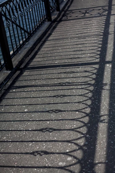 Sombra de diseños de barandilla sobre asfalto — Foto de Stock