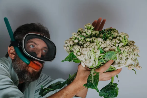 Man in swimming mask is holding  cauliflower